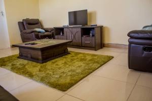 a living room with a table and a tv at Lynm Residence Villas in Harare