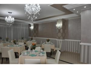 a dining room with white tables and chairs and chandeliers at Hotel Inn in Giardini Naxos