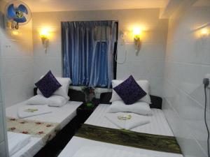 a room with two beds and a window with purple pillows at Paris Guest House in Hong Kong
