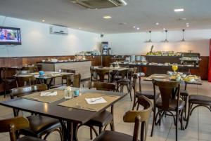 a dining room with tables and chairs in a restaurant at Ponta Negra Beach Melo Flat in Natal