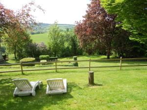 two white chairs sitting in the grass near a fence at Gîte "Le Refuge" Dans un Domaine de 7ha Au Calme in Vimoutiers
