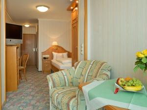 une chambre d'hôtel avec un canapé et une table avec un bol de fruits dans l'établissement Hotel Pension Fent, à Bad Füssing