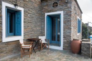 a stone house with blue windows and a table and chairs at Petra Traditional House in Episkopión
