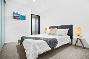 a white bedroom with a large bed and a table at No 5 Rockpool 69 Ave Sawtell in Sawtell