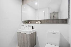 a bathroom with a sink and a toilet and a mirror at No 5 Rockpool 69 Ave Sawtell in Sawtell