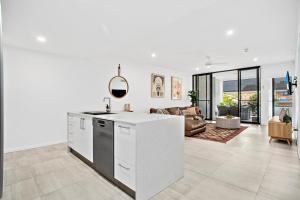 No 5 Rockpool 69 Ave Sawtell في ساوتيل: مطبخ وغرفة معيشة بجدران بيضاء وأريكة