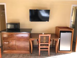 a desk with a television on a wall with a desk with a chair at Bayshore Inn Ventura in Ventura