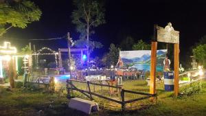 a night scene of a yard with a fence and lights at Banrai Kunchay Wangnamkhiao in Ban Huai Nam Khem