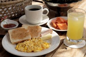 a plate of breakfast food with toast and a cup of orange juice at Hotel Plaza Roma in Ríohacha