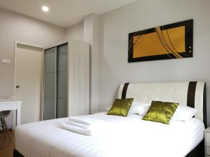 a white bedroom with two beds with green pillows at Omni Cassia Hill Resort in Cameron Highlands
