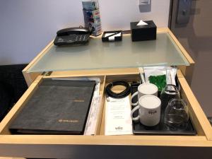 a desk with a phone and a cup and a coffee maker at Hotel Gracery Asakusa in Tokyo