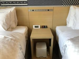 Hotel Gracery Asakusa في طوكيو: طاولة صغيرة بين سريرين في غرفة