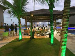 un gruppo di persone seduti in un ristorante con luci verdi di Polinésia Flat Muro Alto Porto de Galinhas a Porto De Galinhas