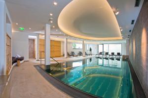 a swimming pool in a house with a large ceiling at Hotel Lukas in Fiss