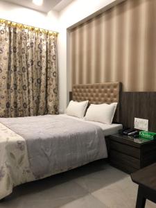 um quarto com uma cama grande e uma cortina em Hotel Antique - Colaba em Mumbai