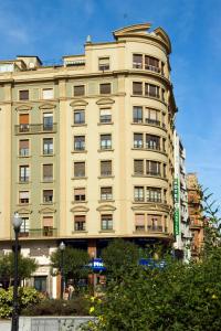 un palazzo alto con un cartello verde davanti di Hotel Castilla a Gijón