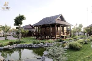 une maison en bois avec un étang en face de celle-ci dans l'établissement THƯ DUY Resort, à Cà Mau