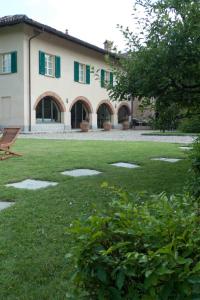 ein Haus mit grünen Rollläden und einem Rasenplatz in der Unterkunft La Giribaldina Winery & Farmhouse in Calamandrana