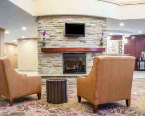 a lobby with two chairs and a stone fireplace at Comfort Suites Cicero - Syracuse North in Cicero