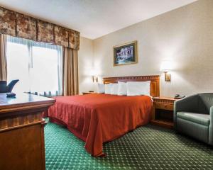 a hotel room with a bed and a chair at Econo Lodge Glens Falls - Lake George in Glens Falls
