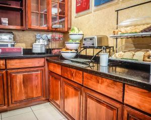 una cocina con armarios de madera y una barra con comida en Quality Inn & Suites Roswell, en Roswell