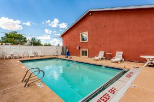 a swimming pool in front of a red building at Quality Inn in Los Lunas