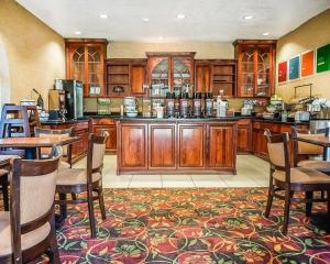 a large kitchen with wooden cabinets and tables and chairs at Quality Inn & Suites Roswell in Roswell