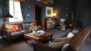 a living room with couches and a table and a fireplace at Troldhaugen Lodge - Adults Only in Jindabyne