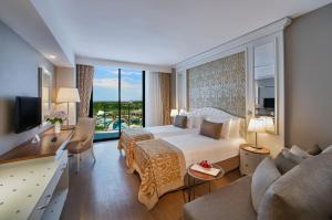 クンドゥにあるアスカ ララ リゾート ＆ スパ ホテルのベッドと大きな窓が備わるホテルルームです。