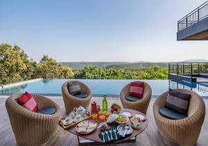 uma mesa com comida e bebidas e cadeiras e uma piscina em SaffronStays Falcon Hill, Lonavala - luxury villa with infinity pool near Lion's Point em Lonavala