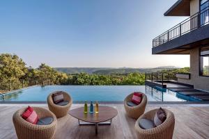 a patio with chairs and a table and a pool at SaffronStays Falcon Hill, Lonavala - luxury villa with infinity pool near Lion's Point in Lonavala