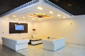 ein Wohnzimmer mit weißen Sofas und einem Flachbild-TV in der Unterkunft Hotel Elegance in Neu-Delhi