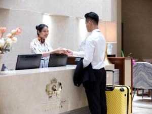 a man and a woman shaking hands at a counter at Royal Star Apartment(Guangzhou Central City Branch) in Guangzhou