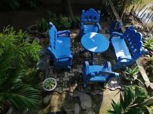 Viveka Inn Guest and Yala Safari في تيساماهاراما: مجموعة من الكراسي الزرقاء والطاولات في الحديقة