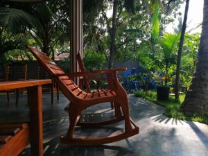 a wooden rocking chair sitting next to a table at Viveka Inn Guest and Yala Safari in Tissamaharama