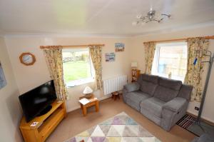ein Wohnzimmer mit Sofa und Fernseher in der Unterkunft Beadnell Cottage in Beadnell
