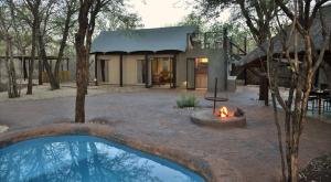 a house with a fire pit in front of it at Jackalberry Ridge by Dream Resorts in Marloth Park