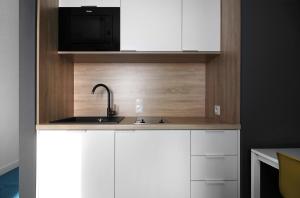a kitchen with white cabinets and a sink at Lemon Plaza Hotel in Poznań