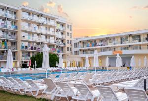 una piscina con sillas y sombrillas frente a un hotel en Hotel Garden Nevis - All Inclusive, en Sunny Beach