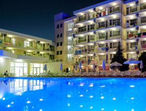 a large swimming pool in front of a hotel at night at Hotel Garden Nevis - All Inclusive in Sunny Beach