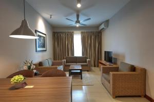 a living room with a couch and chairs and a tv at Acappella Suite Hotel, Shah Alam in Shah Alam