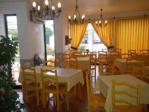 a restaurant with tables and chairs and yellow curtains at Hotel Passagem do Sol in Moura