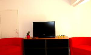 Hostel Amfora في فاجانا: غرفة معيشة مع كرسيين حمر وتلفزيون بشاشة مسطحة