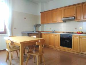 una cocina con armarios de madera, mesa y fregadero en MELAX Apartment, en Tassullo