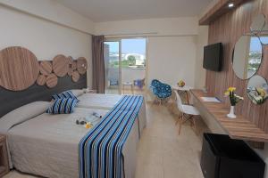 a bedroom with a bed and a desk and a television at Nelia Beach Hotel & Spa in Ayia Napa