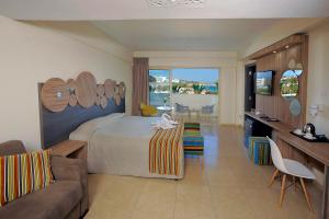 a bedroom with a bed and a living room with a couch at Nelia Beach Hotel & Spa in Ayia Napa