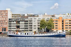 una barca blu e bianca nell'acqua con edifici di Mps Holland ad Amsterdam