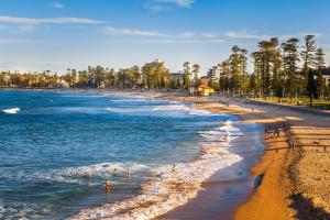 a beach with people walking on the sand and water at Lotus Stay Manly - Apartment 29G in Sydney +5 photos