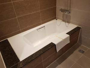 釜山的住宿－Suntree Hotel，瓷砖浴室设有白色浴缸。