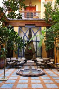 une cour avec une fontaine, des tables et des chaises dans l'établissement Riad Soundouss, à Marrakech